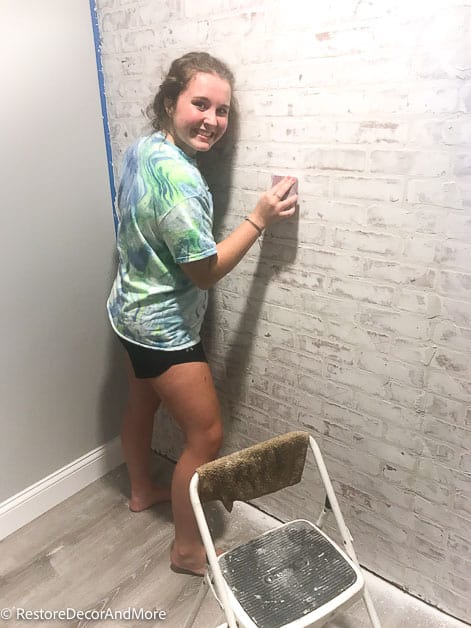 girl sanding faux brick wall 