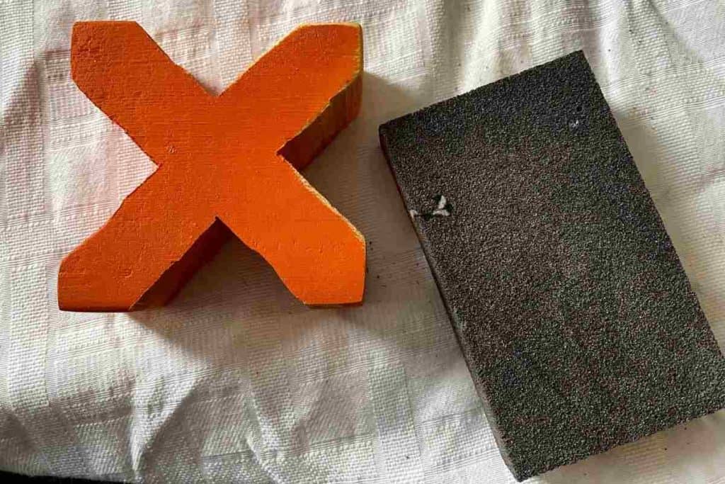 orange wooden letter x and sandblock