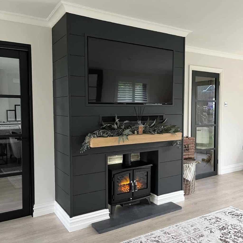 black shiplap fireplace with tv, wood mantle