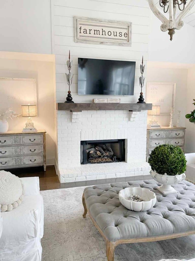 white brick and shiplap fireplace with farmhouse sign and tv mounted