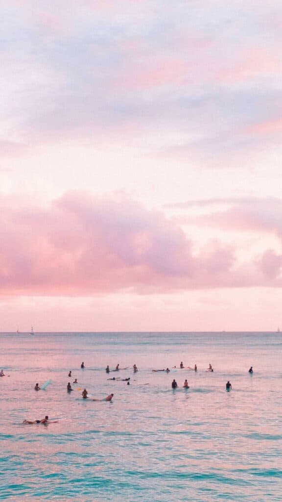 people in water at beach pink clouds