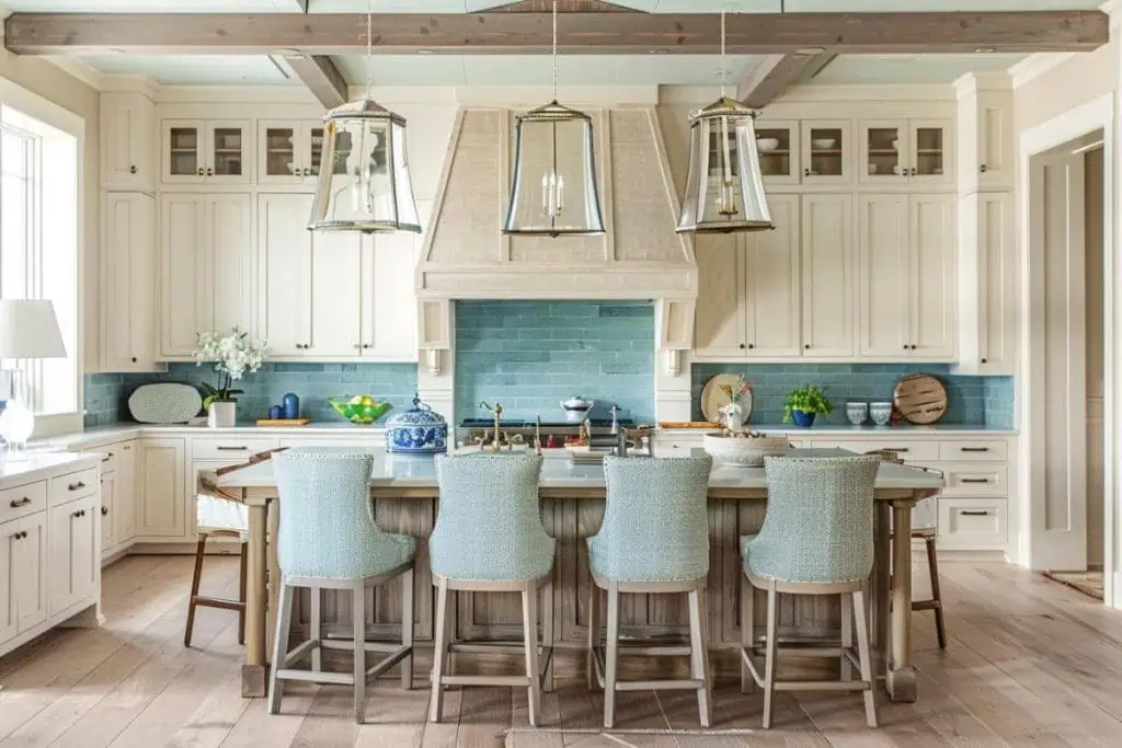 kitchen featuring a coastal blue backsplash, white cabinets, and lantern-style pendant lights above a wood-topped island.