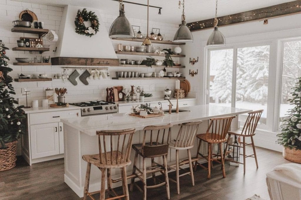 Bright farmhouse kitchen with white cabinetry and a central island surrounded by wooden chairs and Christmas decorations.