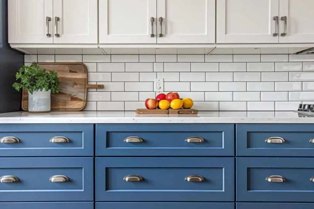 Classic kitchen design with two-toned cabinets, navy blue lower cabinets, white uppers, and subway tile backsplash with open wooden shelving.
