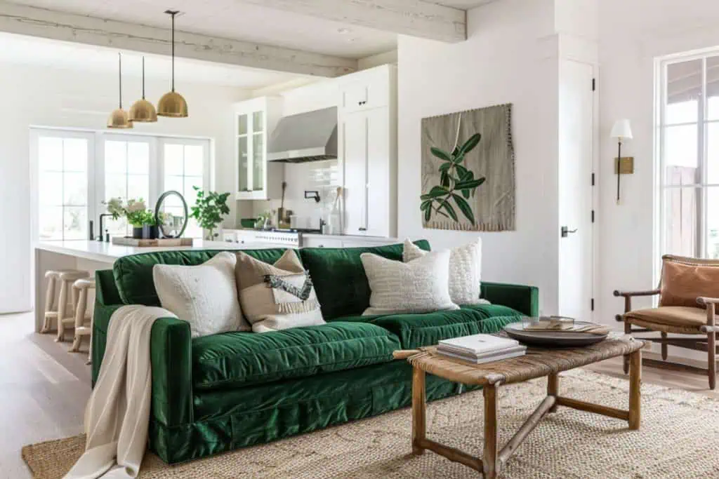 Inviting living room with a green velvet sofa set against a backdrop of white paneled walls and a large contemporary artwork. The space is complemented by a wooden coffee table and chic decorative pillows, offering a blend of comfort and artistry.